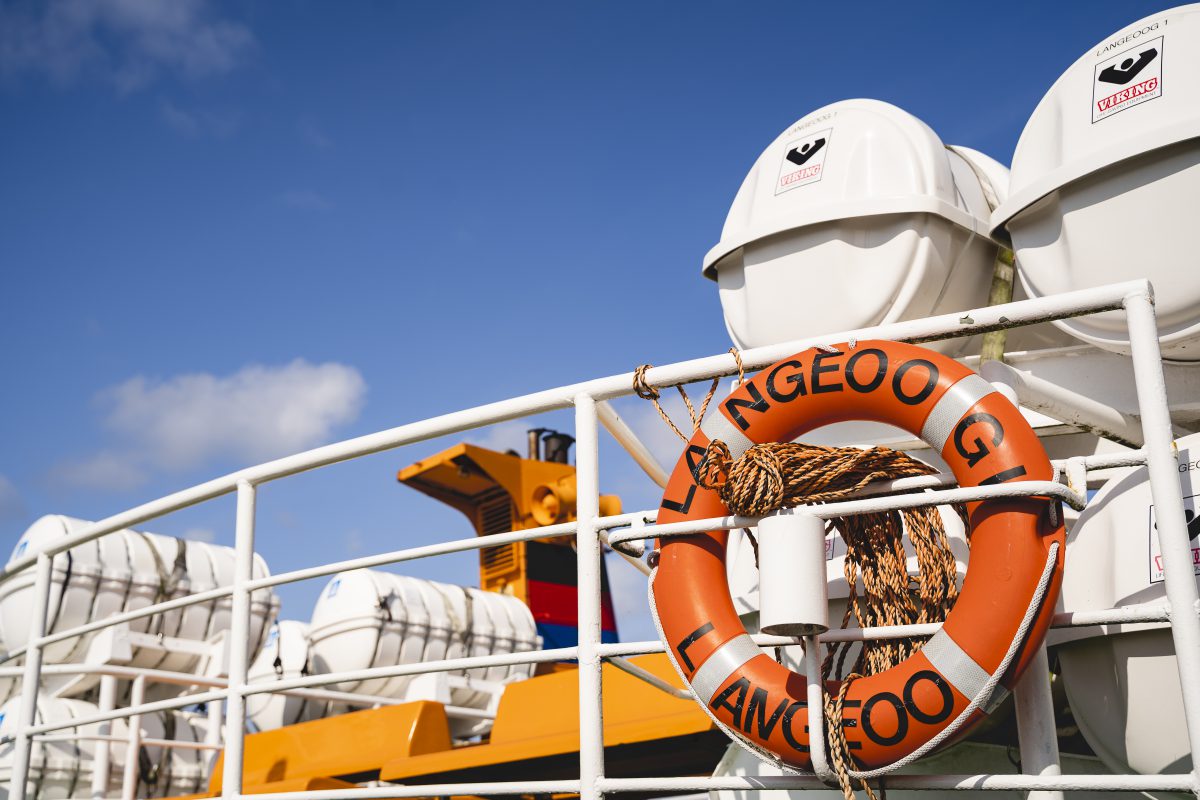 Die Sicht auf eine Fähre mit einem orangenen Rettungsring mit der Aufschrift "Langeoog"